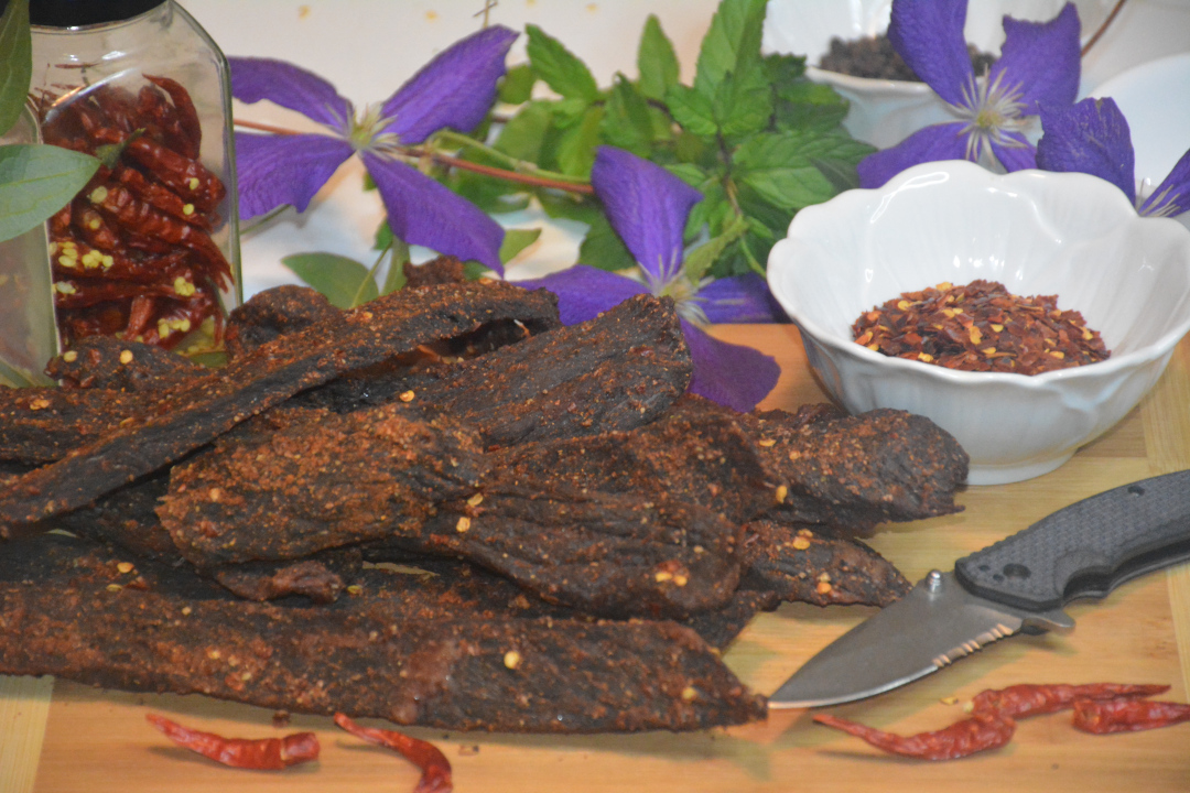 Photo of biltong, peppers, and spices on a cutting board